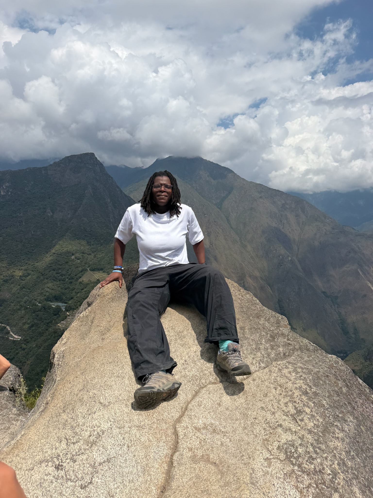Sitting atop Huayna Picchu in Peru, with Machu Picchu and the surrounding mountains behind